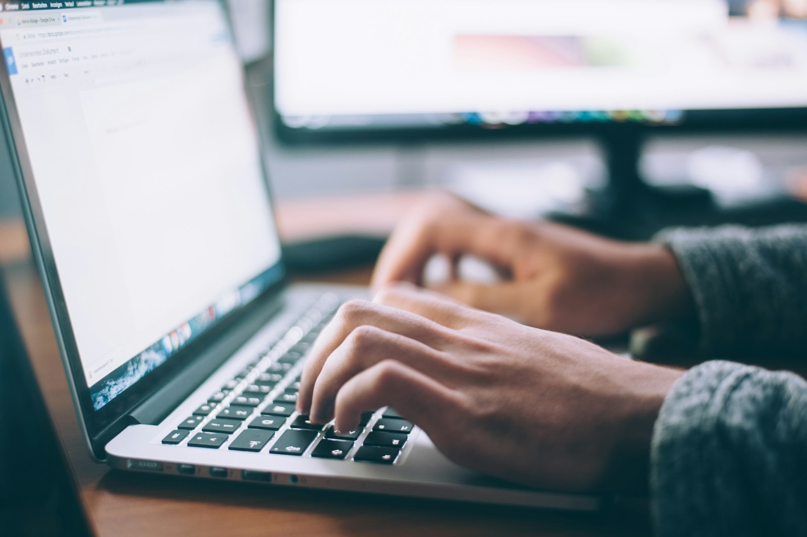 Person working on a laptop with coffee and notebook for focused work